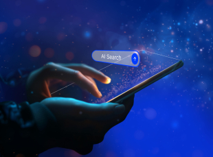 Mano che tocca lo schermo di uno smartphone con l’interfaccia digitale “AI Search” su sfondo blu luminoso, simbolo di ricerca intelligente basata su intelligenza artificiale.